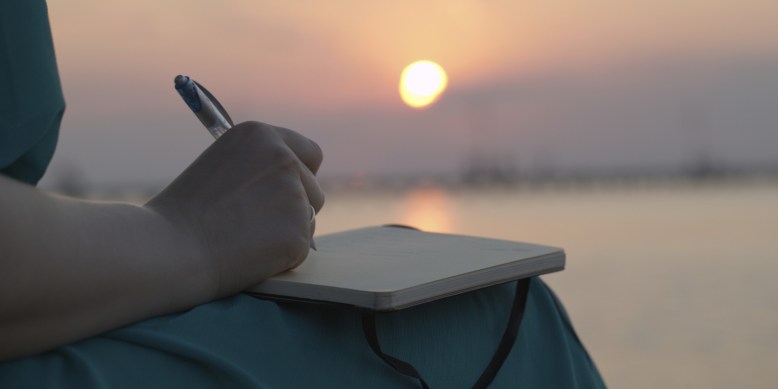Woman writing in her diary at sunset